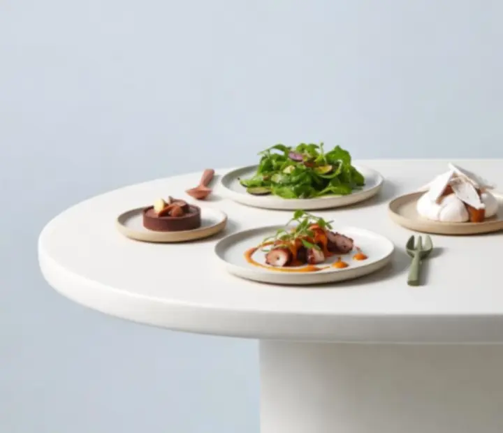 Clay-styled plates of seasonal Australian dishes arranged for sharing on a poker table